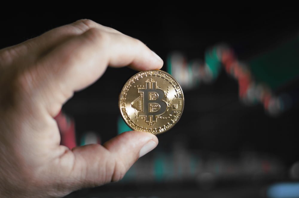 Moneta z symbolem i wykresy w tle jako symbol inwestowania w bitcoin