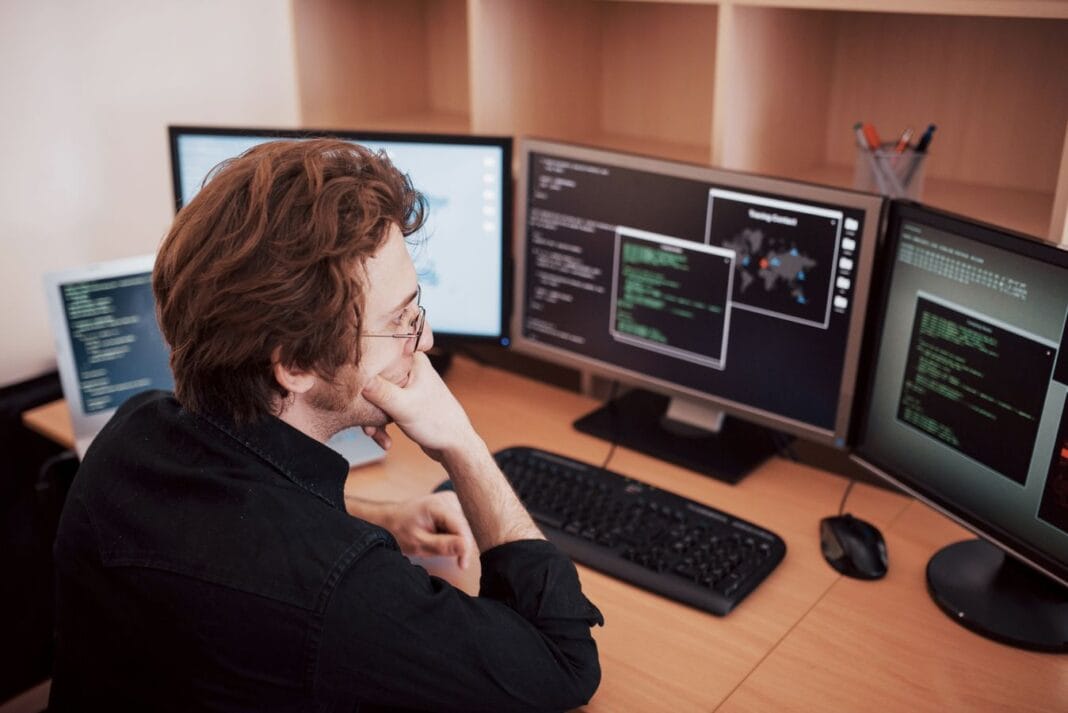 Male programmer working on desktop computer with many monitors at office in software develop company. Website design programming and coding technologies