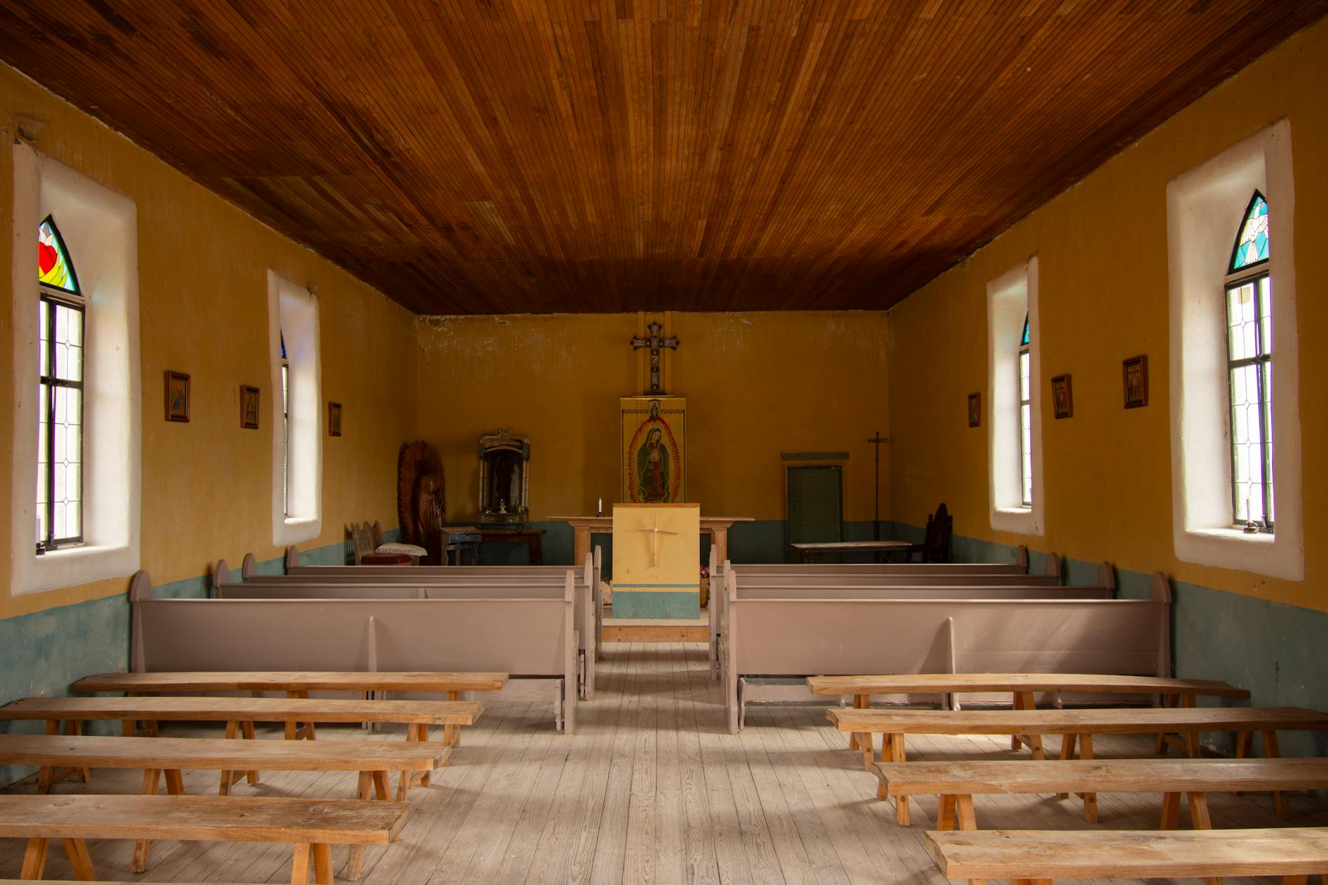 Wnętrze zabytkowego kościoła z drewnianymi ławkami i ołtarzem