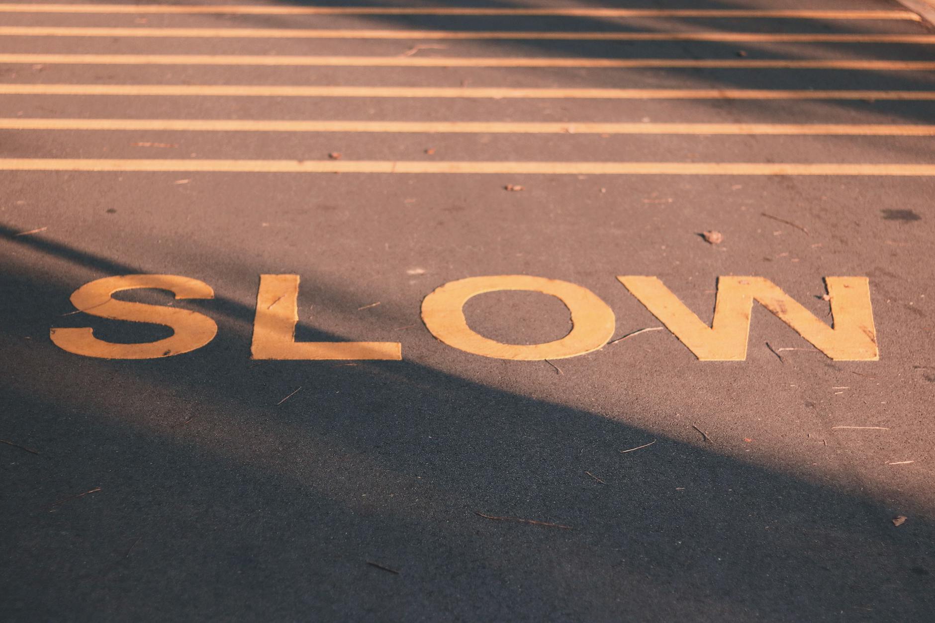 Zbliżenie na drogę z żółtym napisem slow na spokojnej ulicy Singapuru