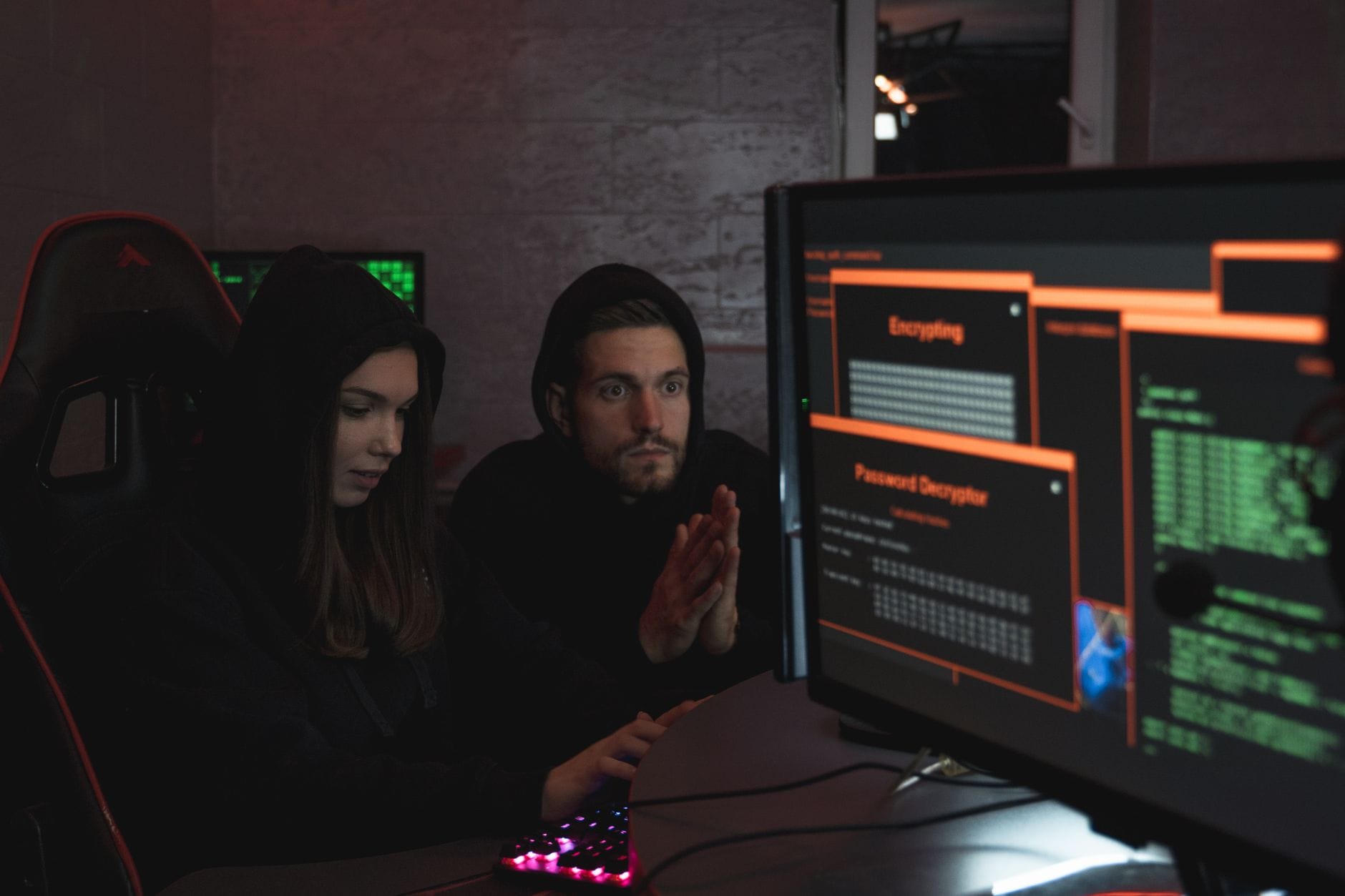 Specjaliści od cyberbezpieczeństwa w kapturach analizują dane na monitorach